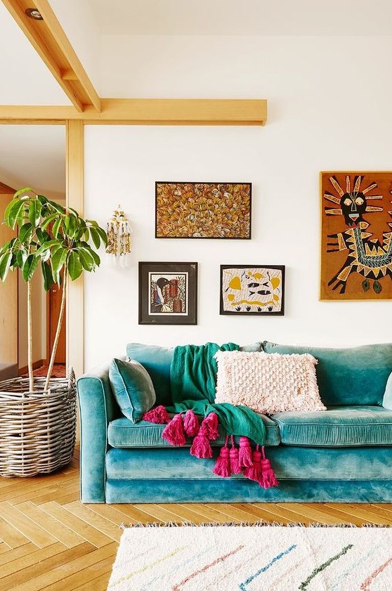 a bright boho living room with a turquoise sofa, bright textiles, a bright boho gallery wall and a potted plant in a basket