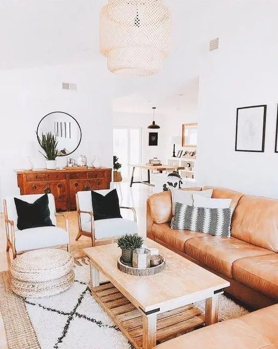 a bright boho living room with an amber leather sofa, a low coffee table, creamy chairs, jute poufs and potted plants
