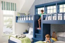 a bright kids’ room with built-in navy bunk beds, white and green bedding, a ladder, an accent wall and striped pieces