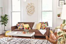 a bright living room with a brown sofa, butterfly chairs, a catchy coffee table, bright printed textiles and a chandelier