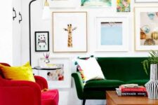 a bright living room with a green loveseat, a red chair, a stained coffee table, a brigth gallery wall and a printed rug