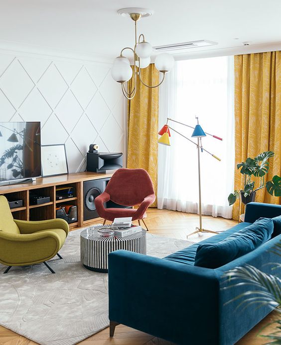 a bright mid-century modern living room with a stained storage unit, a coral and mustard chair, a navy sofa, a side table and colorful lamps