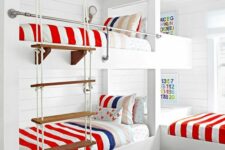 a bright seaside kids’ room with multiple bunk beds, bright bedding and a bold rug, a rope ladder and some colorful decor