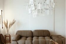 a catchy boho living room with a brown low sofa, a glass coffee table, pampas grass and a chandelier with notes