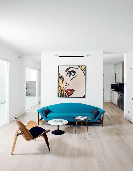 a catchy living room with much negative space, a statement artwork, a turquoise sofa, a plywood chair and tables