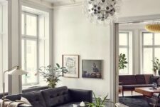 a catchy mid-century modern living room with a black leather sofa, a coffee table, a black chair, a bubble chandelier