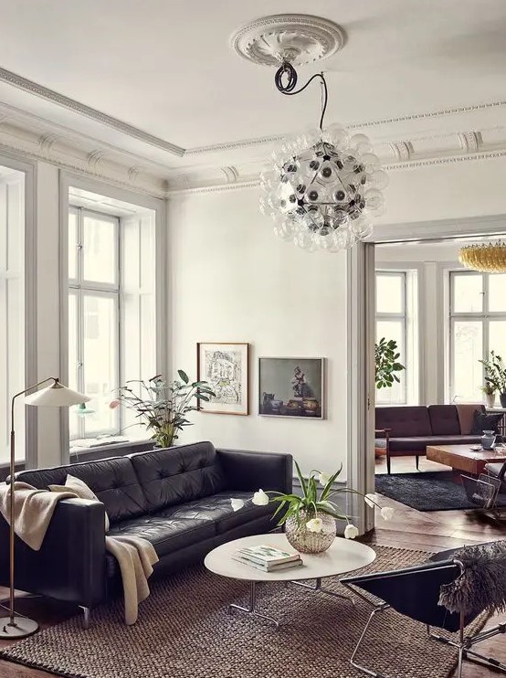 a catchy mid century modern living room with a black leather sofa, a coffee table, a black chair, a bubble chandelier