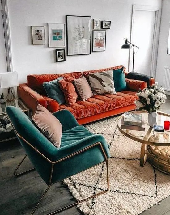 a charming living room with a bold burnt orange modern sofa, a teal chair and matching pillows plus a lovely gallery wall