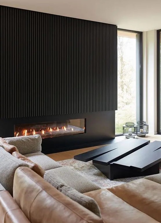 a chic minimalist living room with a black built-in fireplace with black wood over it, a neutral sofa, an eye-catchy black coffee table