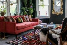 a chic modern living room with graphite grey walls, a modern red sofa, a colorful rug, a black chair and potted cacti is wow