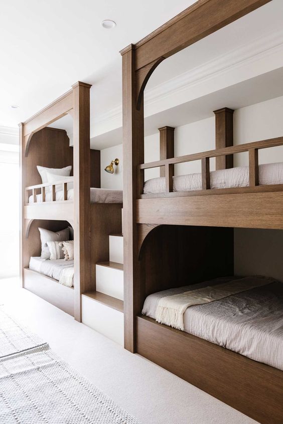 a chic modern rustic kids' room with built-in multiple bunk beds and neutral bedding plus a ladder is a cool and lovely space to be in