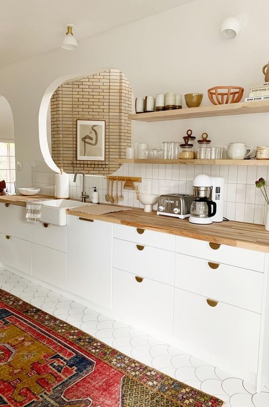 a chic white contemporary kitchen with light stained butcherblock countertops and gold touches looks elegant