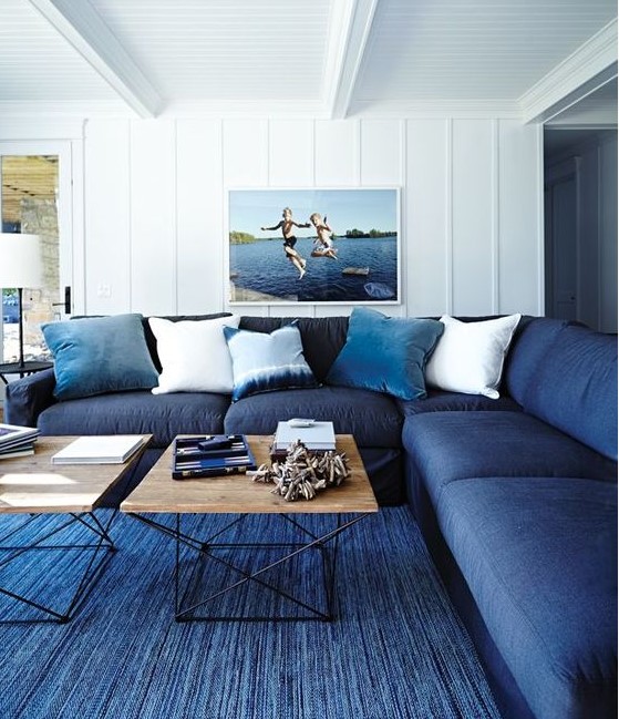 a classic blue rug and a navy sofa plus light blue pillows make the space feel beachy