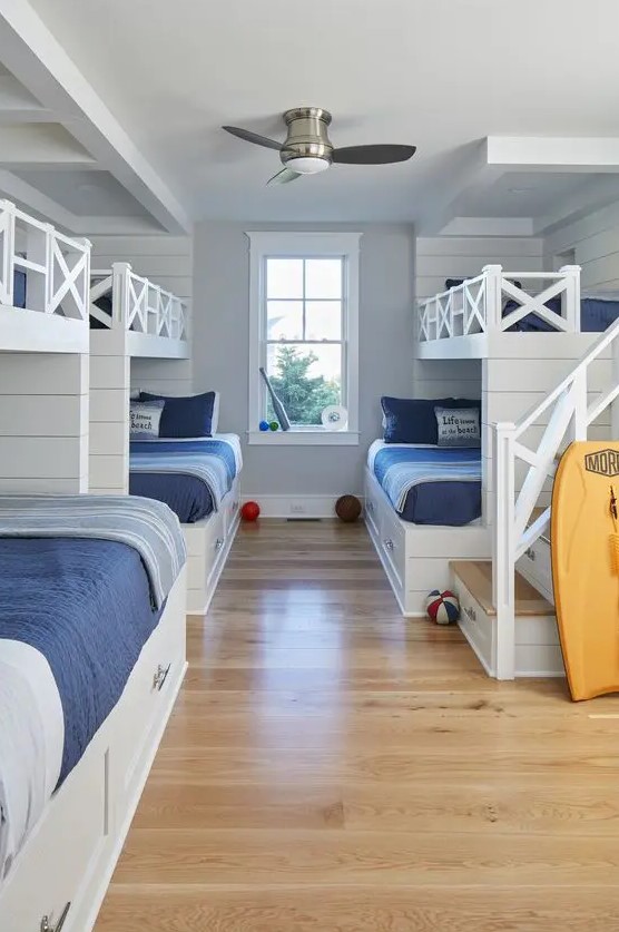 a coastal kids' bedroom with built in bunk beds, navy and blue bedding, built in ladders and a surf