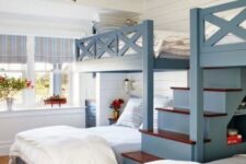 a coastal kids’ room with blue bunk beds with a large ladder, neutral bedding, a red lantern and red touches here and there