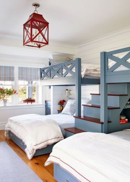 a coastal kids' room with blue bunk beds with a large ladder, neutral bedding, a red lantern and red touches here and there