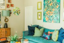a colorful living room with a turquoise sofa, a bright artwork and a gallery wall, a geo hex-shaped table, a bead chandelier