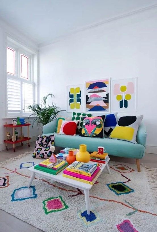 a colorful retro inspired living room with an aqua sofa, a colorful rug, a gallery wall, pillows and books fill the space with bright colors