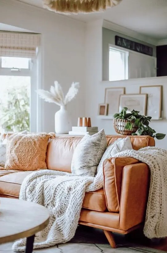 a comfy amber leather sofa styled with knit and crochet pillows and blankets is very cozy and inviting