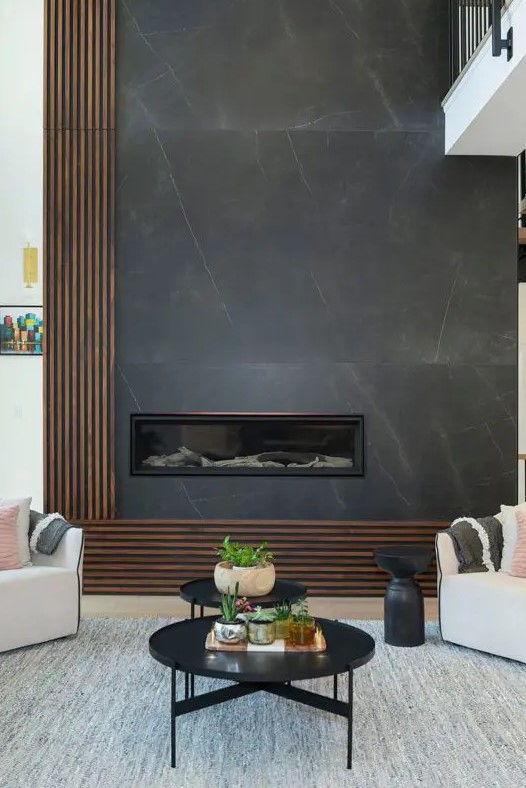 a contemporary living room with a minimalist fireplace clad with grey marble, white seating furniture and black tables