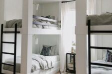 a contemporary neutral kids’ room with two bunk bed units, metal ladders and wall lamps over each bed