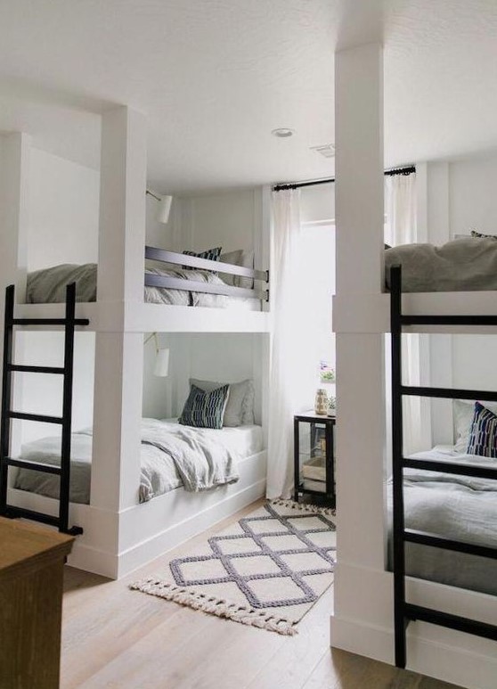 a contemporary neutral kids' room with two bunk bed units, metal ladders and wall lamps over each bed