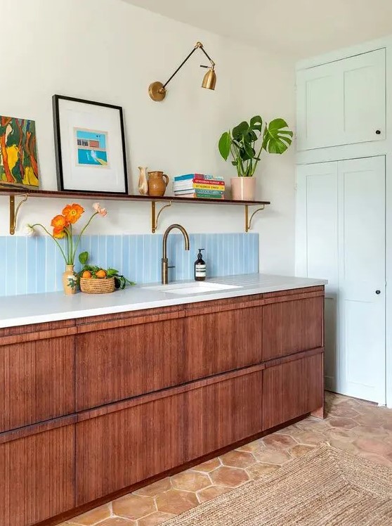 a cool and chic mid century modern kitchen with stained cabinets, white stone countertops, an open shelf, artwork and books and potted plants