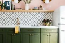 a cool and vivacious kitchen with lower green cabinets, a geo tile backsplash, a long open shelf used for displaying art and decor