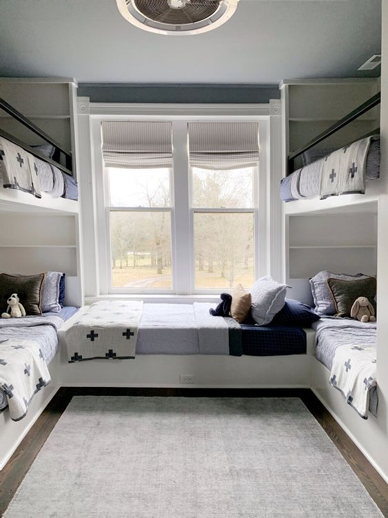 a cool kids' room with multiple bunk beds, neutral and printed bedding, a grey rug is a stylish and cool space