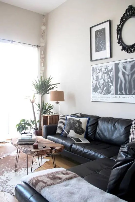 a cool living room with a black leather sectional, a living edge coffee table, a gallery wall and a cowhide rug