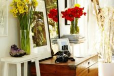 a cool nook with a stained chest as a console table and a storage unit, a tall mirror, photos in frames and blooms