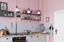 a cozy and lovely pink and grey kitchen with pink walls, a grey backsplash and cabinetry, a printed tile floor and pendant lamps
