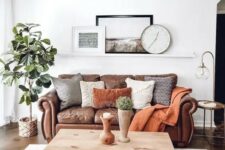 a cozy boho living room with a brown leather sofa and lots of pillows, a hairpin leg coffee table and baskets, a potted tree