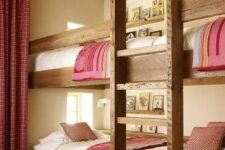 a cozy rustic kids’ room with four built-in bunk beds, with a ladder and pink and white bedding, with matching curtains and a rug