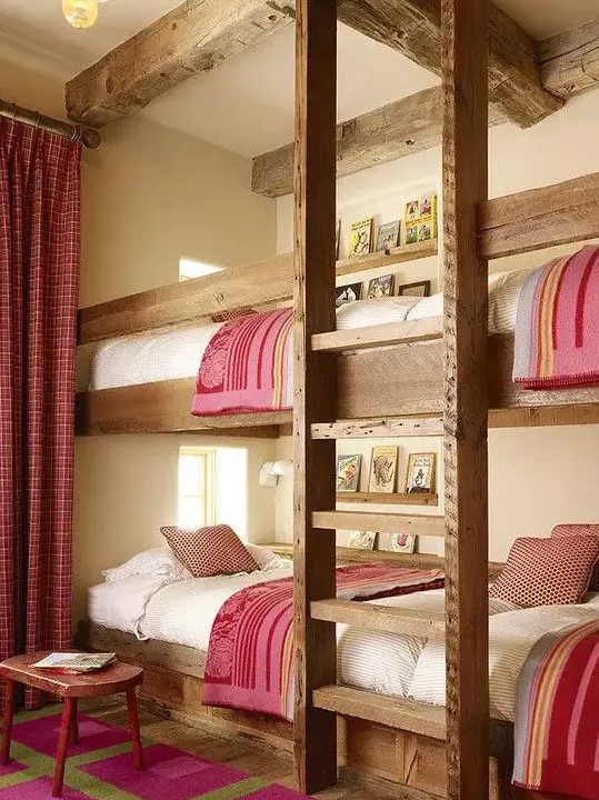 a cozy rustic kids' room with four built in bunk beds, with a ladder and pink and white bedding, with matching curtains and a rug