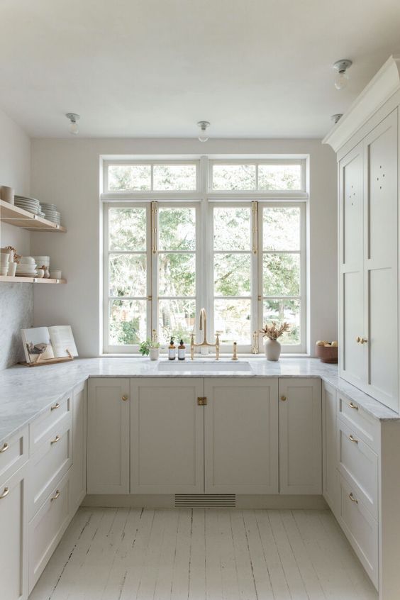 a creamy U-shaped kitchen with casement windows, shaker style cabinets and open shelves is a lovely and cozy space