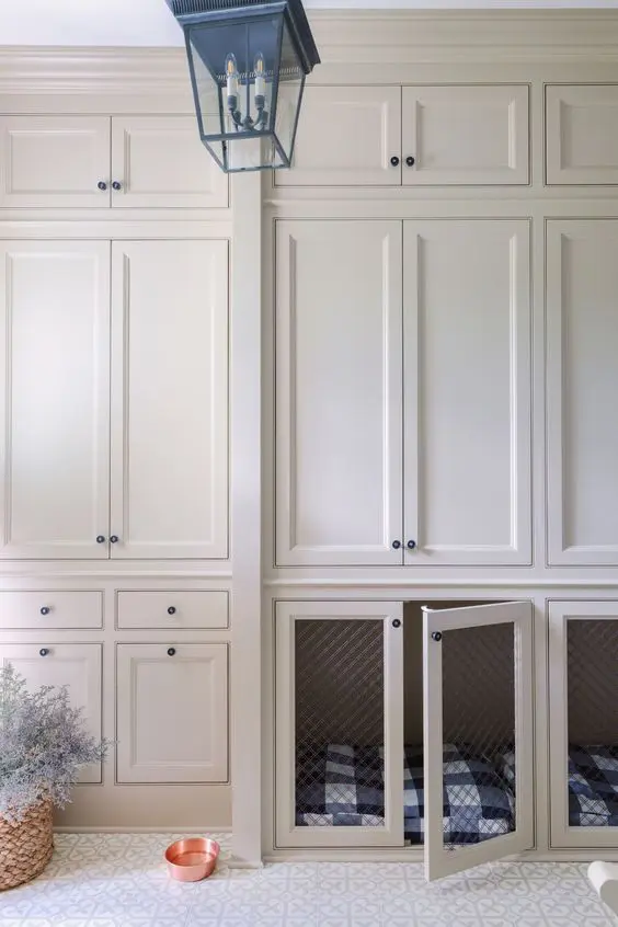 a creamy mudroom with shaker style cabinets and lower cabinets with built-in dog crates is a cozy and cool space