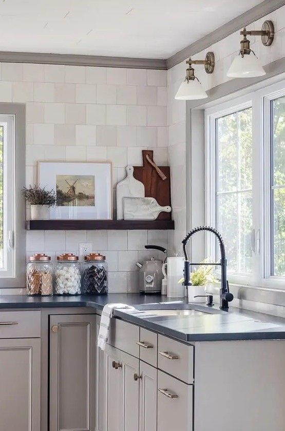 a dove grey kitchen with flat panel cabinets and shaker style ones, black soapstone countertops, an open shelf and a square tile backsplash