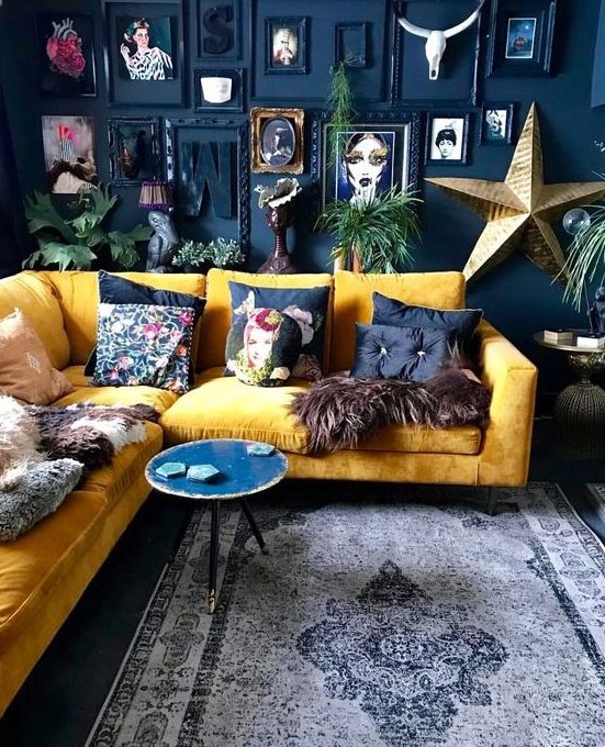 a dramatic living room with a navy accent wall, a bold gallery wall, a yellow sectional and bright pillows plus a round table