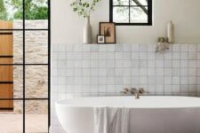 a farmhouse bathroom with neutral tiles, a terracotta tile floor, an oval tub, a glass door to the garden and neutral textiles