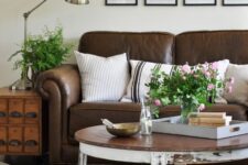 a farmhouse living room with a brown leather sofa, a stained file cabinet, a shabby chic coffee table and a grid gallery wall
