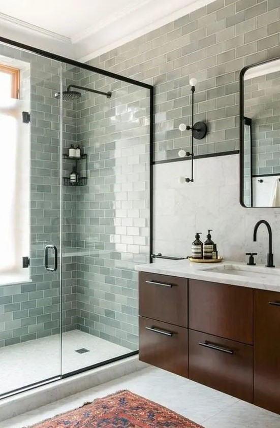 a farmhouse sage green bathroom clad with subway tiles, a dark-stained floating vanity and black fixtures