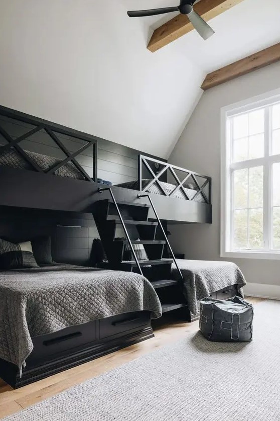 a laconic farmhouse kid's room with black built in bunk beds and a ladder, graphite grey bedding and a pouf
