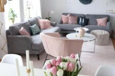 a light-filled Scandi living room with grey sofas, pink pillows and a chair, a couple of coffee tables
