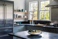 a light grey kitchen with flat panel cabinets and a kitchen island, black soapstone countertops and a backsplash, wooden beams and open shelves