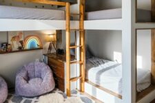 a lovely kids’ space with multiple bunk beds, a sitting zone with purple chairs and a neon sign, layered rugs