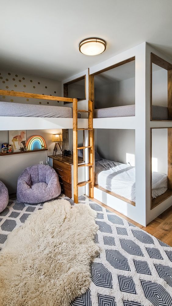 a lovely kids' space with multiple bunk beds, a sitting zone with purple chairs and a neon sign, layered rugs