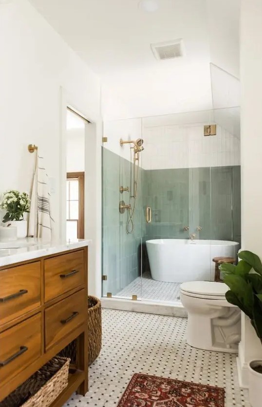a mid-century modern bathroom with sage green tiles in the bathing zone, a printed tile floor, a stained vanity and a basket