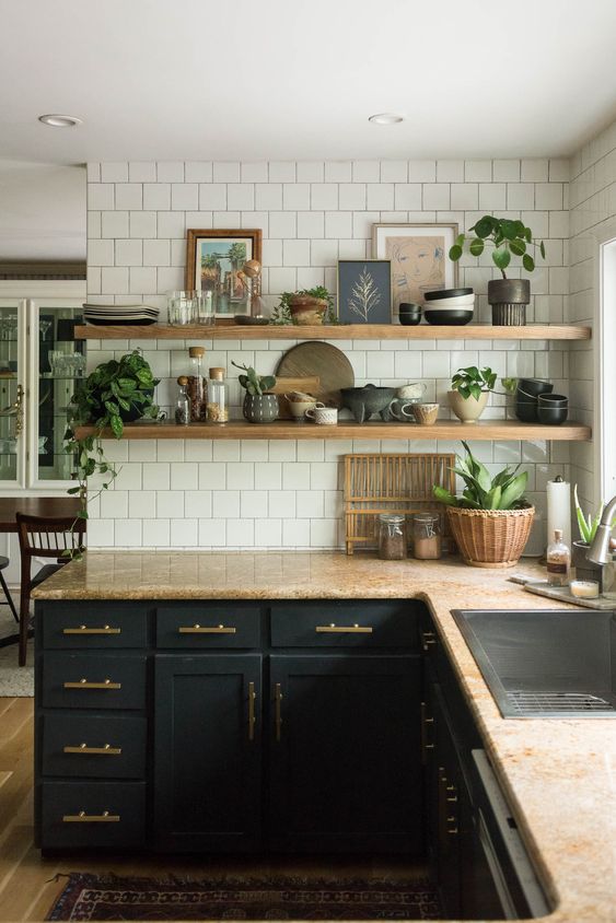 a mid century modern kitchen with black shaker cabinets, beige granite countertops, white square tiles and open shelving