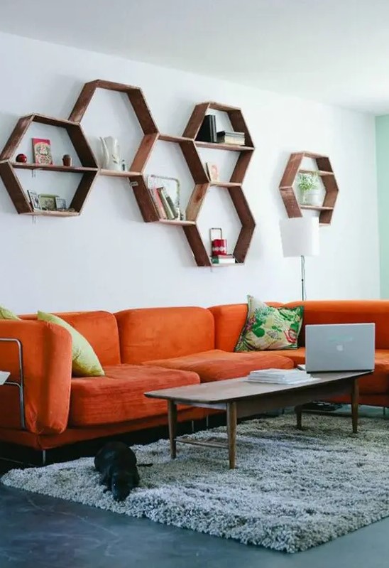a mid-century modern living room with a modern orange sofa, hexagon shelves, a low table and colorful pillows is welcoming